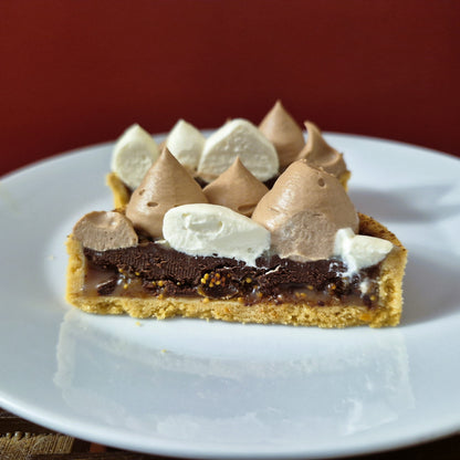 Slice of dessert tart with chocolate, cream, and cookie layers on a white plate.